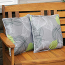 Two decorative throw pillows add cushion to a wooden garden bench on a patio.