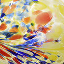 Yellow glass gazing ball with splashes of blue, red and orange.