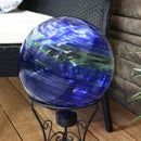 Blue swirl gaze globe in a stand sitting on a wood patio.