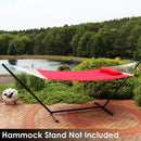 Red quilted hammock on a hammock stand sitting on a brick patio.