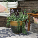 Single two-tone yellow and blue planter filled with spiller-type plants next to a brown wicker patio chair with green striped cushions.