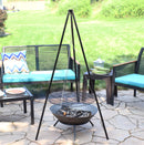 Tripod fire pit cooking grate set warming up over a fire.