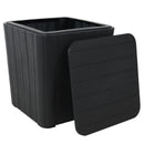Black, faux woodgrain side table with storage with lid off, resting on the side of the box.