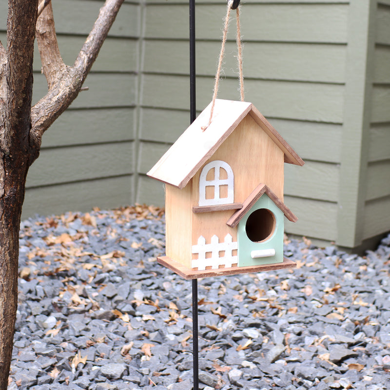Birdhouse with painted window and fence hanging from a hook.