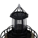 Close-up of a weathered brown and green lighthouse statue featuring a black lantern, glass enclosure, solar panel, and metal railing against a white background.