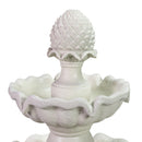 Close-up of the top tier of an off-white decorative outdoor water fountain, featuring a pinecone-shaped finial and scalloped basin.