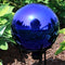 Blue mirrored surface gazing ball displayed in the backyard.
