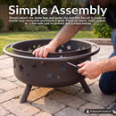 Bronze Cosmic Fire Pit shown during assembly on a stone patio, with a person securing the outer rim to the fire bowl using a screwdriver, highlighting the simple assembly process.
