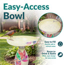 Mosaic Bloom Glass Bird Bath in rainbow shown outdoors in a garden with a bird perched on the wide, shallow bowl. Open bowl design provides easy access for filling with water and room for birds to drink and bathe.