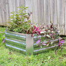 Square, silver raised garden bed outside with plants growing inside