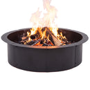 Black metal circular fire pit ring filled with burning logs and flames, shown on a white background.