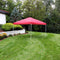 Red 12'x12' pop up canopy with white frame set up on a backyard lawn.