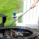 Fire poker with wood handle being used to stir hot logs in a fire pit.