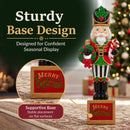 Green and red Christmas nutcracker holding a wreath and candy cane, standing on a decorative “Merry Christmas” base with a close-up callout highlighting the supportive base and stable placement on flat surfaces.