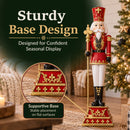 Red and gold Christmas nutcracker king holding a gold scepter, displayed indoors beside a decorated Christmas tree, with a close-up callout highlighting the supportive base and stable placement on flat surfaces.