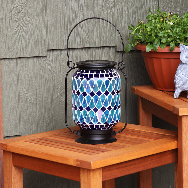 Blue mosaic lantern sitting on a wooden table.