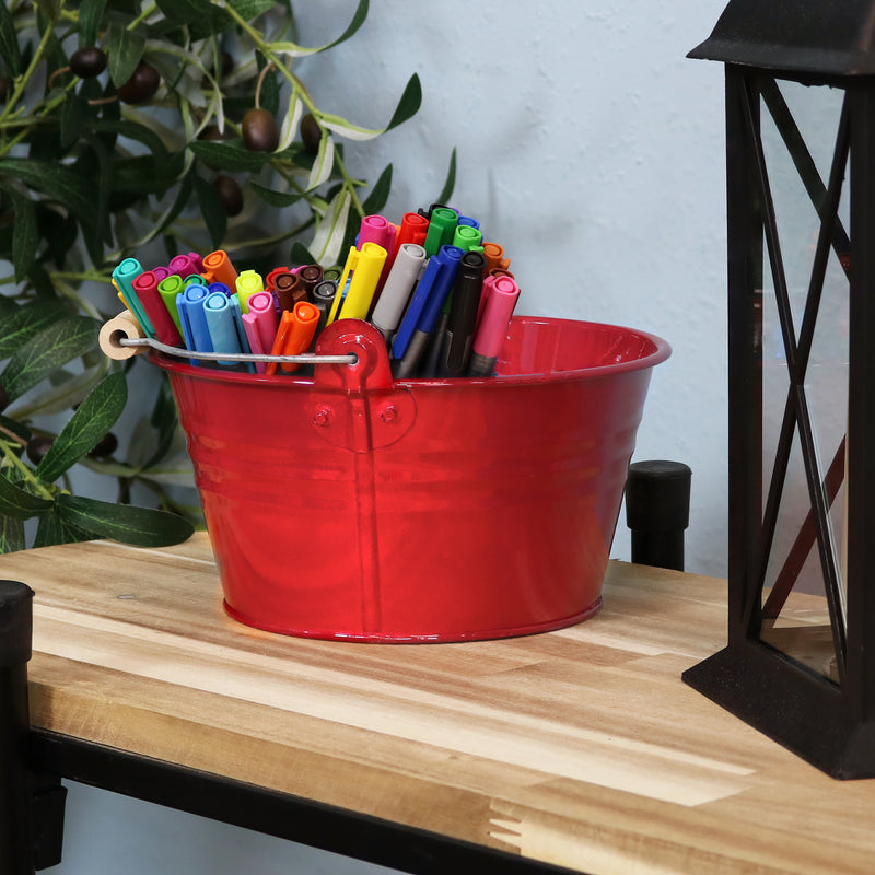 
Four red galvanized steel buckets with handle filled with various items placed bookshelf containing books and pictures.
