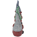 Back view of a stacked Christmas gnome statue showing the patterned blue, green, and gray hats, red clothing, and white background.