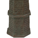 Close-up of a weathered brown and green lighthouse statue showing the brick-textured base, raised center detail, and small door.
