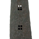 Close-up of a weathered brown and green lighthouse statue showing two four-pane cutout windows and a textured finish.