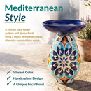 Mediterranean-style glass bird bath with a glossy blue bowl and vibrant two-toned blue, orange, and cream patterned pedestal. Text highlights its vibrant color, handcrafted design, and unique focal point.