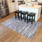 5 x 7 blue striped indoor rug laid out on a hardwood floor in front of kitchen island with three square black bar stools