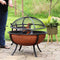 A lit copper-colored fire pit spark screen being remove by a fire poker.