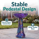 Crackled Glass Mosaic Bird Bath in iridescent purple shown outdoors on a patio, featuring a secure bowl connection and a wide, stable pedestal base.