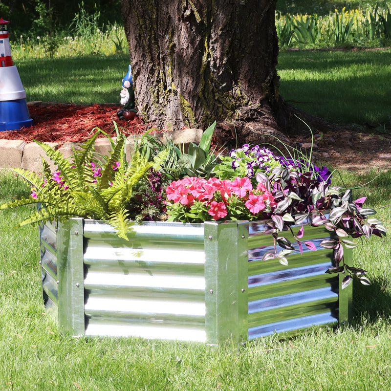 Silver, metal garden bed full of lush flowers sitting in a backyard.