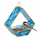 Modern Mosaic Fly-Through Bird Feeder in blue filled with birdseed, with a small black, white, and gray songbird perched on the edge of the open feeder.