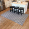 5x7 gray lattice style indoor rug laid out over hardwood floor next to kitchen island with square black bar stools
