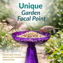 Purple glass birdbath filled with birdseed, with two birds perched on the bowl. Text highlights its unique garden focal point, vibrant color, dramatic patterns, and handcrafted artisanal finish.