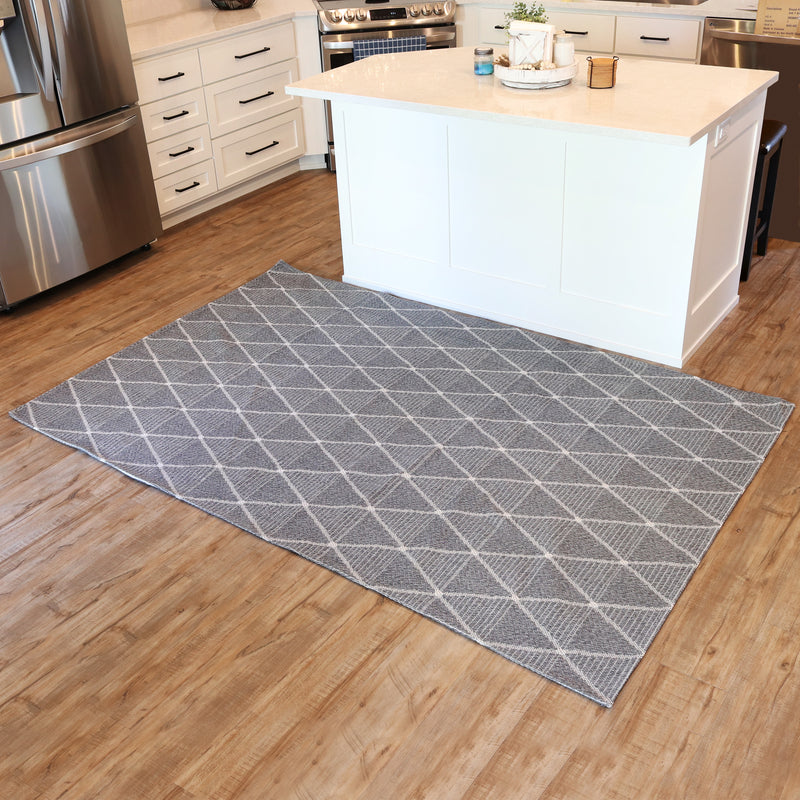 5x7 gray lattice style indoor rug laid out over hardwood floor in front of kitchen island