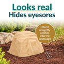 Tan artificial landscape rock with realistic sandstone texture displayed in a mulched garden with decorative stones and greenery, designed to conceal unsightly outdoor utilities while blending naturally into the landscape.
