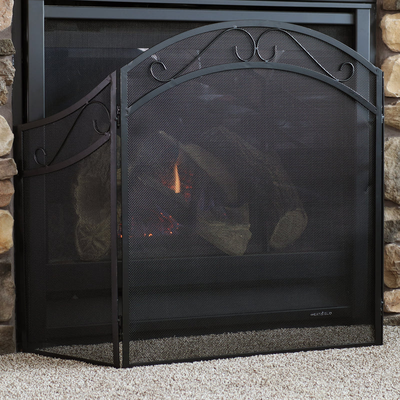 Decorative metal fireplace screen in front of an indoor fireplace to protect rogue sparks and ash.
