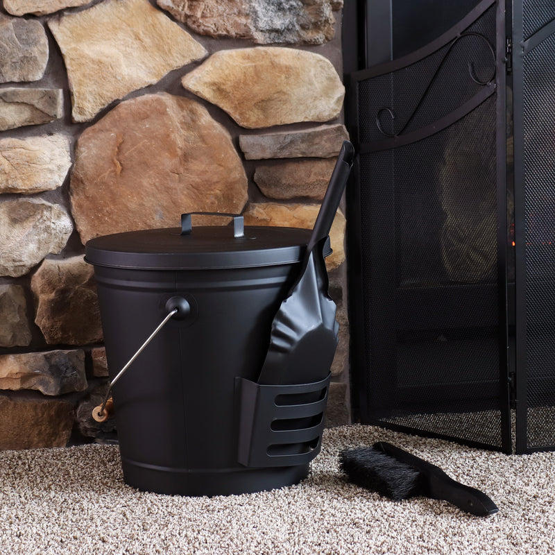 Fireplace ash bucket with lid, shovel and brush placed near indoor fireplace with fireplace screen
