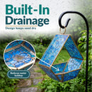 Modern Mosaic Fly-Through Bird Feeder in blue shown hanging outdoors in the rain. Built-in drainage helps reduce water buildup and keeps birdseed drier.