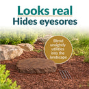 Infographic featuring a flat, dark brown decorative faux rock cover with a realistic stone texture in a mulched garden bed. Text reads “Looks real, Hides eyesores” with a callout explaining how it blends unsightly utilities into the landscape. Three metal ground stakes are displayed beside the rock.