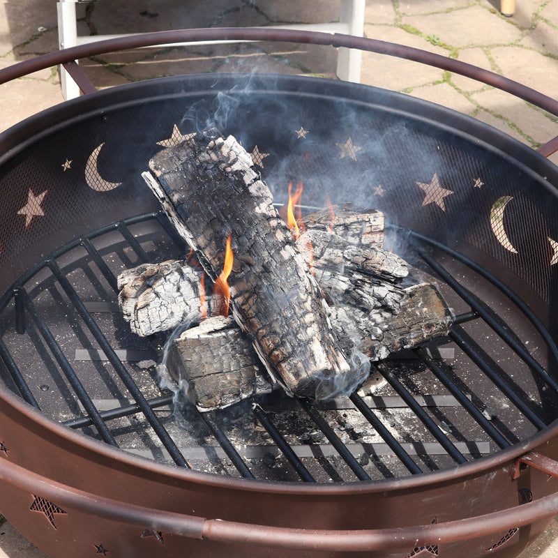 Black, metal wood grate supporting burning logs inside of a bronze fire pit.