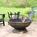 Steel, bronze fire bowl with spark screen burning a fire on a stone patio.