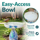 Mosaic Bloom Glass Bird Bath in indigo shown outdoors in a garden with a bird perched on the wide, shallow bowl. Open bowl design provides easy access for filling with water and room for birds to drink and bathe.