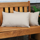 Two dark beige lumbar throw pillows sit on a wooden bench.
