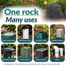 Dark gray faux rock utility cover displayed in a landscaped garden, with examples of eight uses: concealing septic tank covers, well pump risers, sprinkler valves, outdoor outlets, pond filter systems, control panels, spillway boxes, and pipes. Text notes the rock is decorative and should not be sat, stood, or leaned on.
