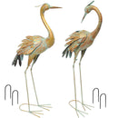 Two blue and gold-colored metal crane statues each with two garden stakes.