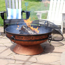 Copper-colored burning fire pit with spark screen resting on the rim.