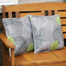 Two decorative throw pillows add cushion to a wooden garden bench on a patio.
