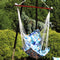 Parrot print hammock seat swing with wooden spreader bar hangs from a hammock chair stand outside