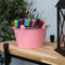 
Four pink galvanized steel buckets with handle filled with various items placed bookshelf containing books and pictures.