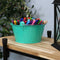 
Four teal galvanized steel buckets with handle filled with various items placed bookshelf containing books and pictures.
