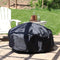 A black round fire pit cover protects an outdoor fire pit on a stone patio.
